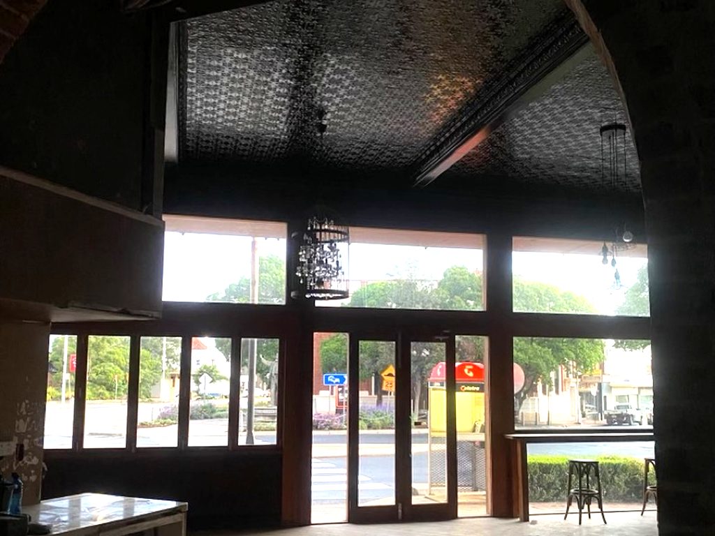 Inside the empty shopfront, timber-framed windows and doors opening onto the street